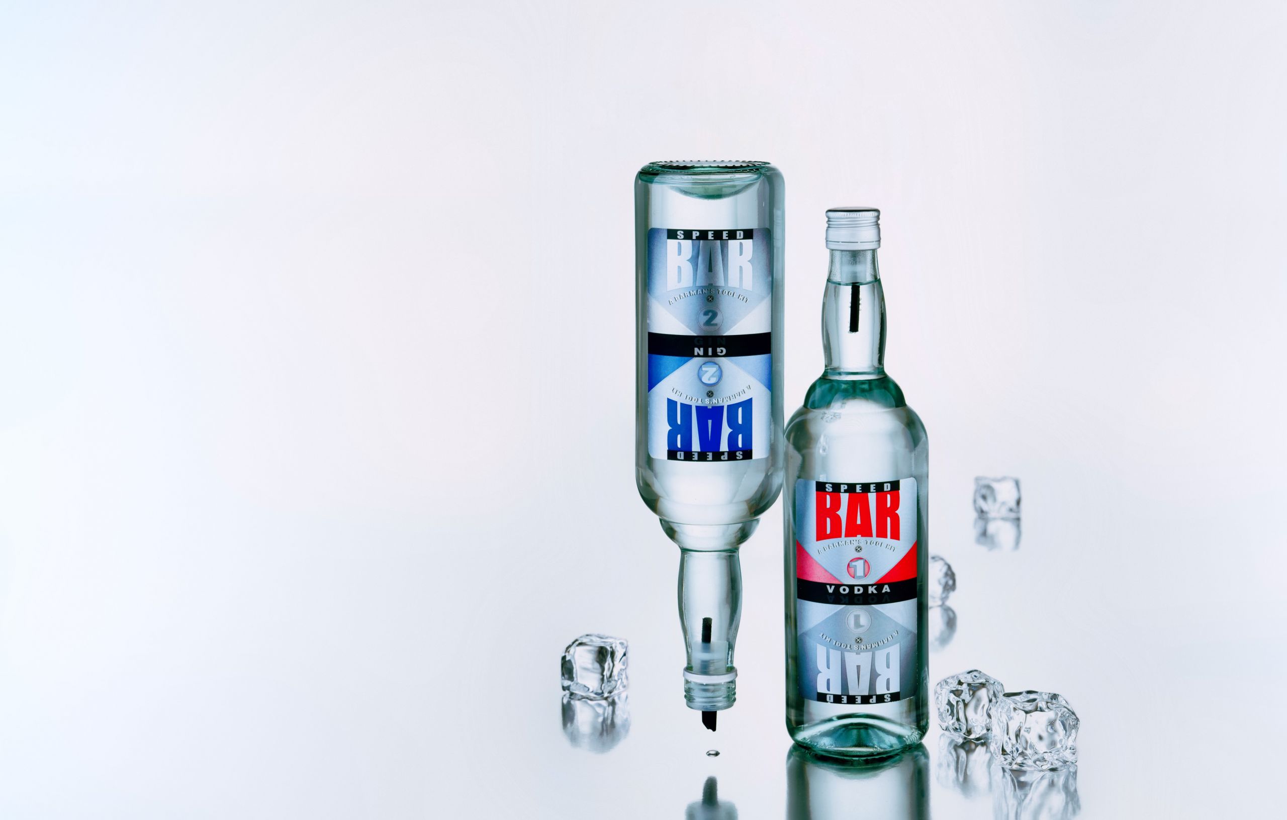 בקבוקי ודקה ג'ין לבר על רקע אפור משתקף בהיר עם קוביות קרח צילום סטודיו רייס צלמים