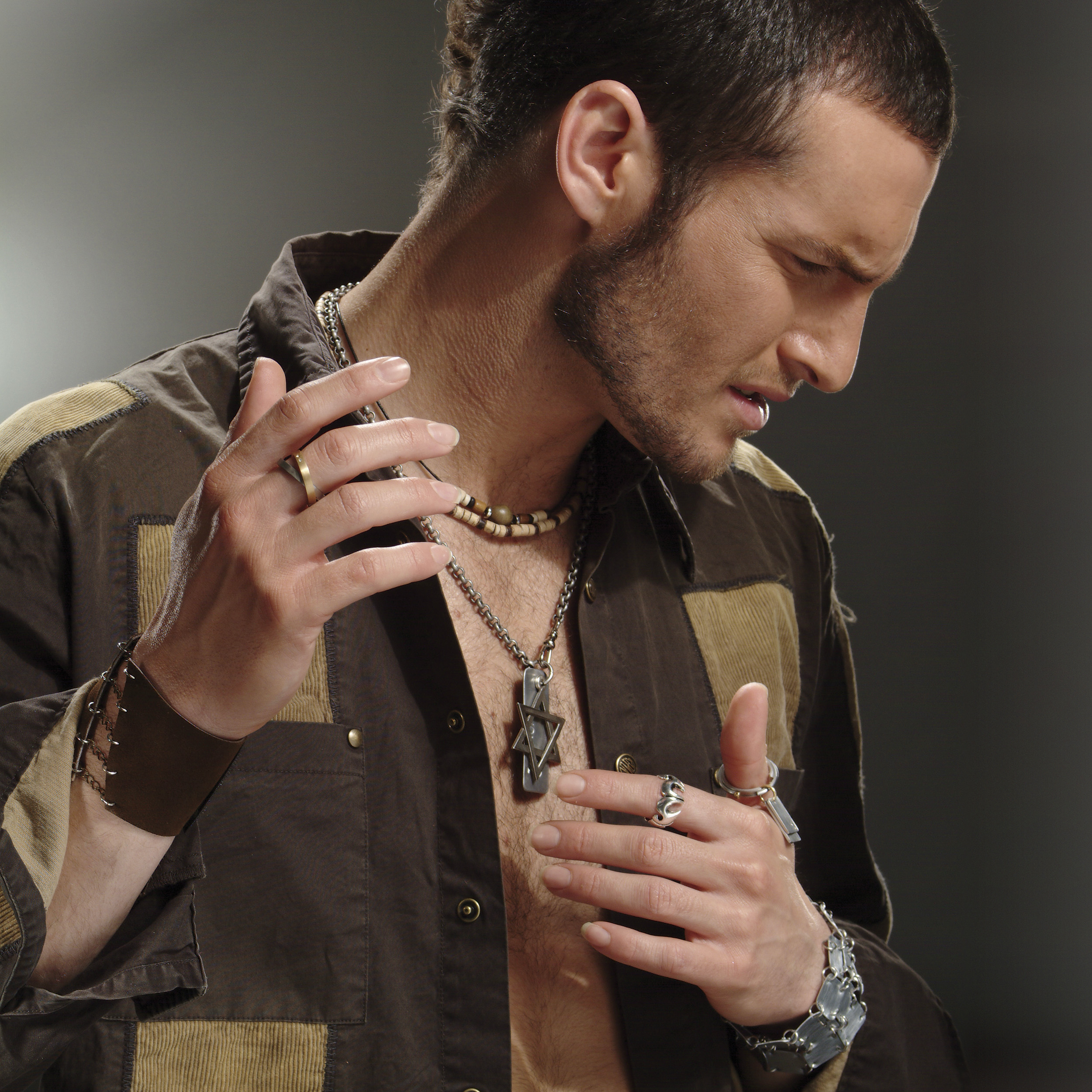 הדוגמן אנחל בונני בצילום מתוך כתבה לעיתון בלייזר עם חולצה חומה שרשרת מגן דוד צמידים טבעות Photo by REISS PHOTOGRAPHERS STUDIO on August 17, 2022. May be an image of 1 person, wrist watch and indoor.