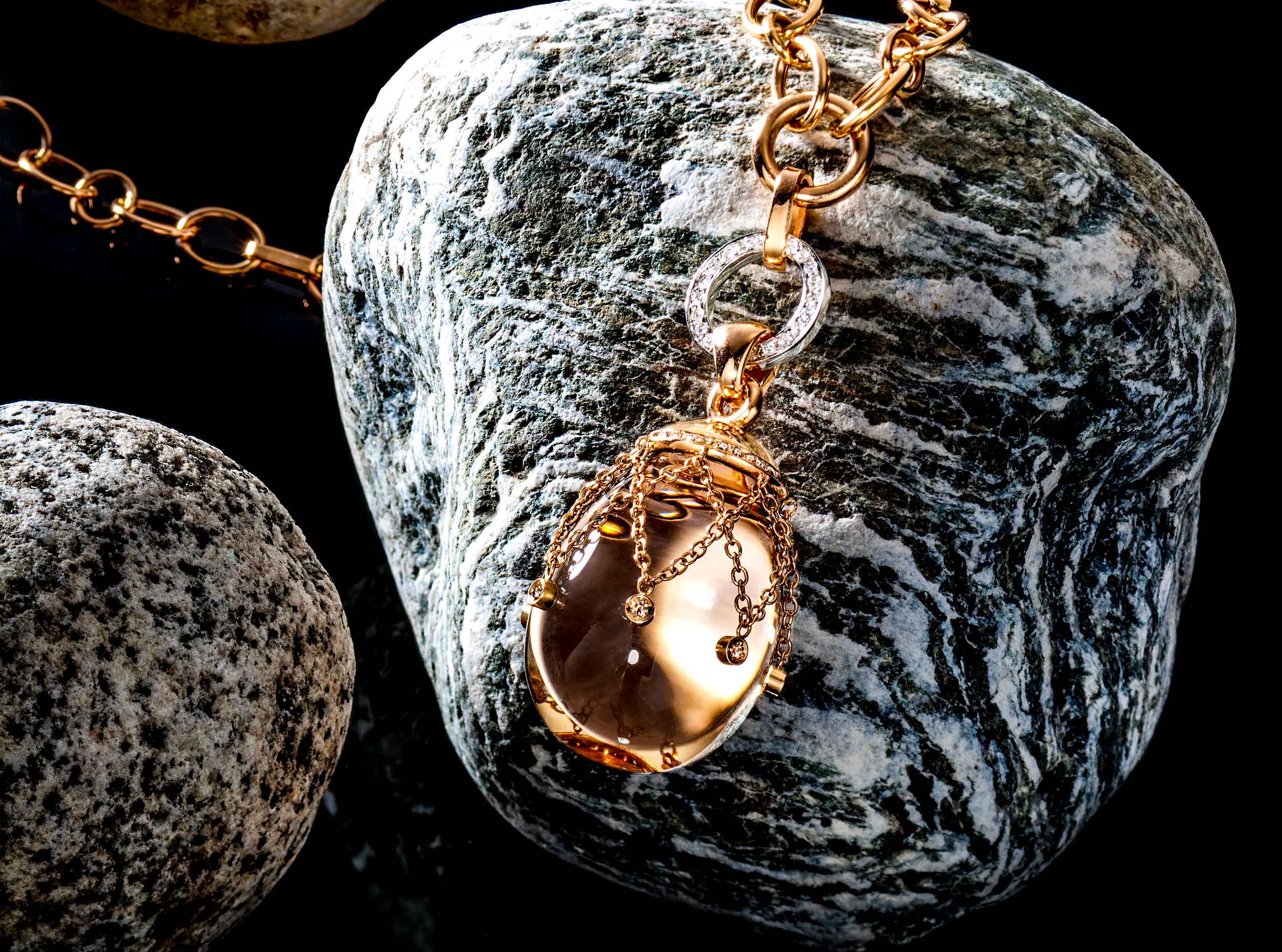 צילום תכשיט שרשרת זהב עם תליון זהב על אבן שקופה עם יהלומים על חלוק נחל על רקע שחור משתקף